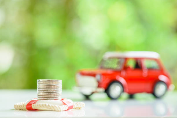 Car or auto insurance concept : Red lifebuoy, life buoy or a life saver, a row of coins and a blurred sedan car on a table. The image depicting protection against financial loss when involved in an accident.